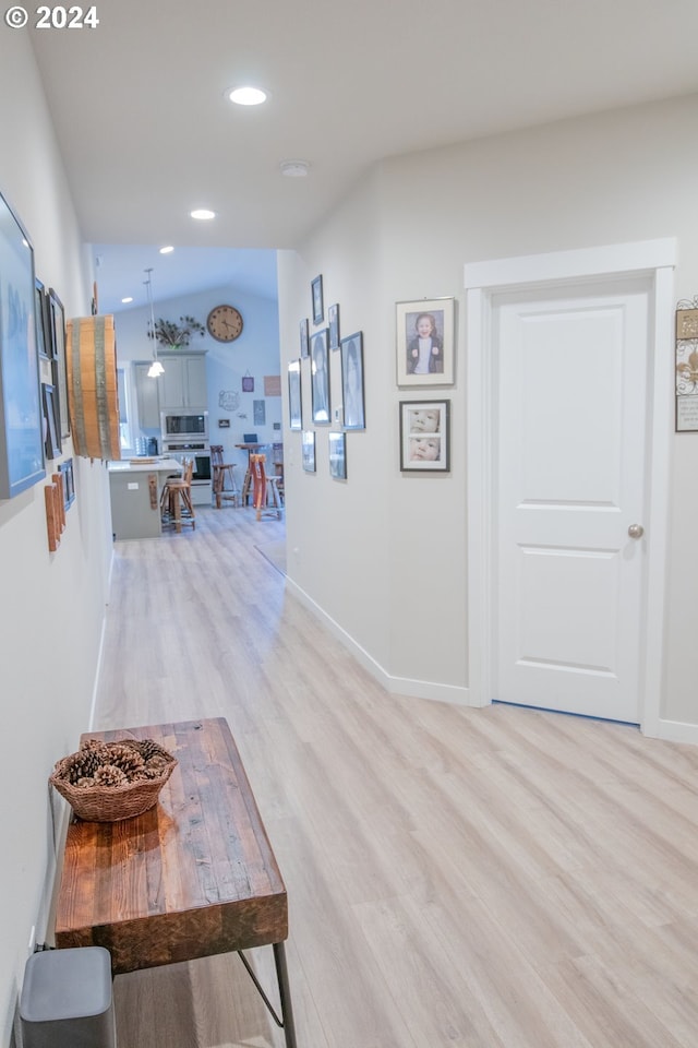 hall featuring vaulted ceiling and light wood-type flooring