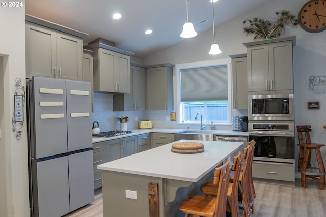 kitchen featuring lofted ceiling, sink, gray cabinets, a kitchen island, and stainless steel appliances