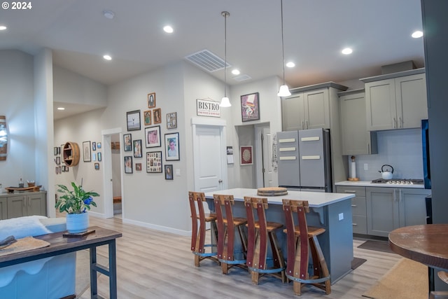 kitchen featuring visible vents, gray cabinetry, backsplash, freestanding refrigerator, and light wood-style floors