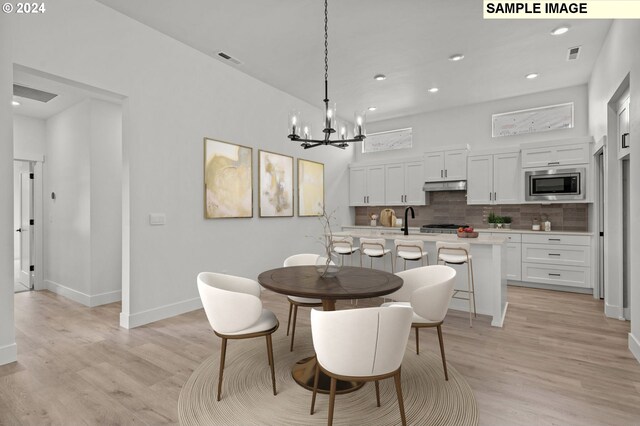 dining area featuring an inviting chandelier, light hardwood / wood-style flooring, and sink