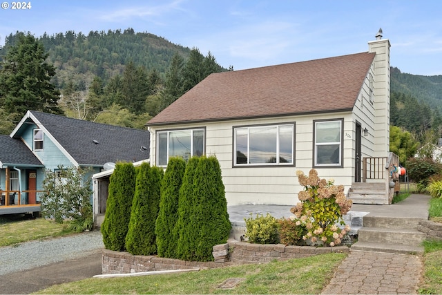 306 Evergreen Ave, Garibaldi, OR 97118 - view of front of house with a chimney, a mountain view, and roof with shingles