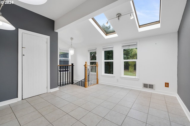 spare room featuring lofted ceiling with skylight and light tile patterned floors