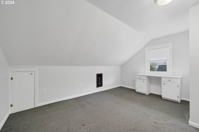 additional living space featuring lofted ceiling and dark carpet