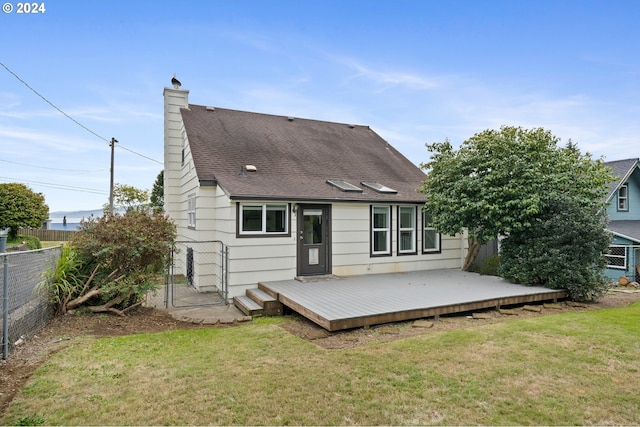 rear view of property featuring a wooden deck and a lawn