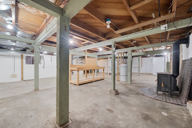 basement with strapped water heater and a wood stove