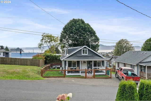 view of front of house featuring covered porch, a front yard, and a mountain view