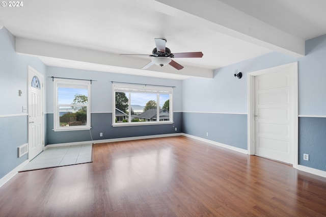 empty room with light hardwood / wood-style floors, beam ceiling, and ceiling fan