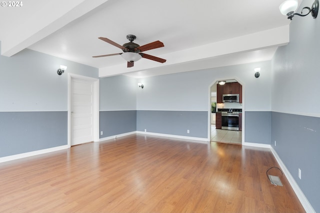 spare room with beam ceiling, light hardwood / wood-style floors, and ceiling fan