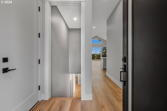 hall featuring lofted ceiling and light hardwood / wood-style flooring