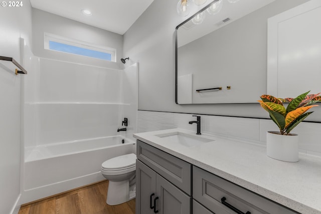 full bathroom with hardwood / wood-style floors, vanity, toilet, and tub / shower combination