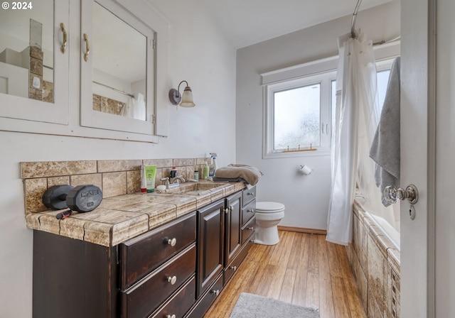 full bathroom with hardwood / wood-style flooring, vanity, toilet, and shower / tub combo