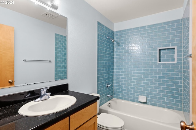 full bathroom with tiled shower / bath, vanity, and toilet