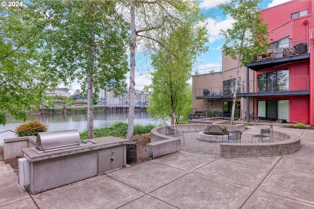 view of patio / terrace with area for grilling, a water view, a fire pit, and a balcony