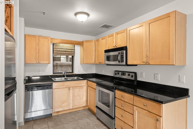 kitchen featuring light brown cabinetry, sink, stainless steel appliances, and light tile floors