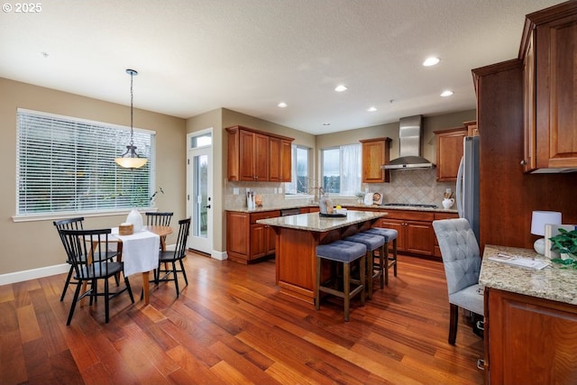 5310 NW Primino Ave, Portland, OR 97229 - kitchen with a kitchen breakfast bar, a center island, brown cabinetry, wall chimney range hood, and dark wood-style flooring