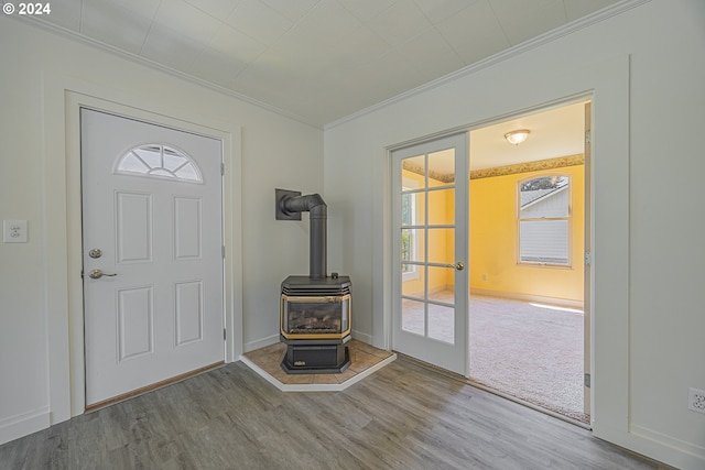 foyer with light wood-type flooring, a wood stove, and ornamental molding