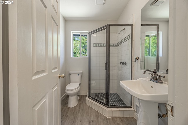 bathroom featuring hardwood / wood-style flooring, toilet, a shower with shower door, and sink