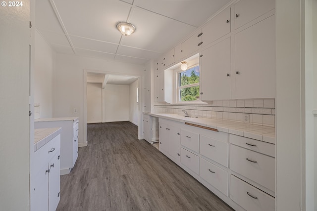 kitchen with tile countertops, sink, decorative backsplash, light wood-type flooring, and white cabinetry