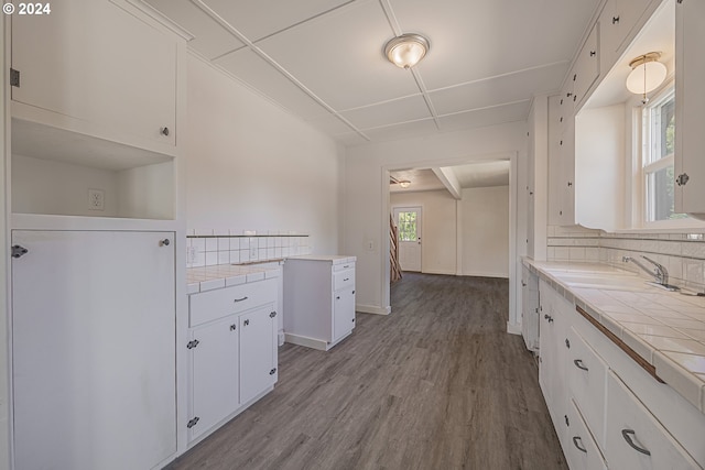 kitchen with tasteful backsplash, sink, tile countertops, white cabinets, and light hardwood / wood-style floors