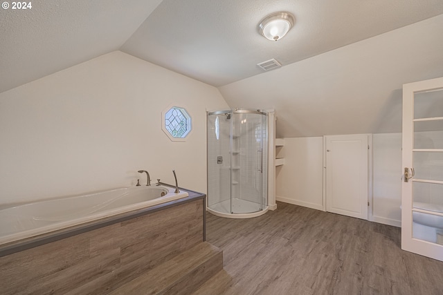 bathroom with a textured ceiling, independent shower and bath, vaulted ceiling, and wood-type flooring