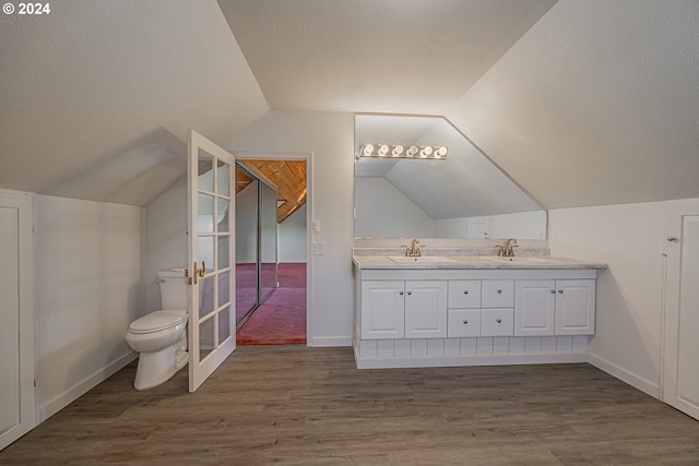 bathroom featuring vanity, vaulted ceiling, hardwood / wood-style flooring, toilet, and a textured ceiling