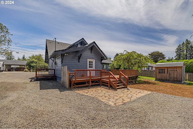 rear view of property with a storage unit, a patio, and a wooden deck