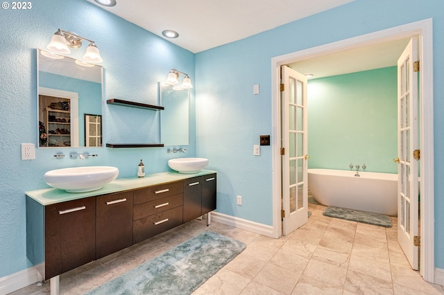 bathroom featuring french doors, vanity, and a tub