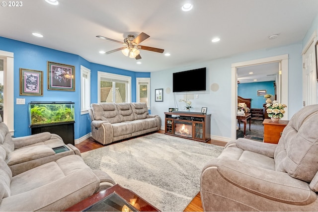 living room with ceiling fan, a fireplace, and hardwood / wood-style flooring