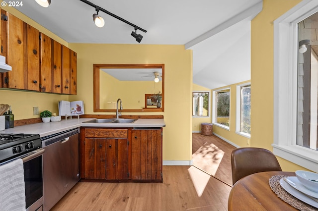 kitchen with light wood-type flooring, sink, lofted ceiling, appliances with stainless steel finishes, and track lighting