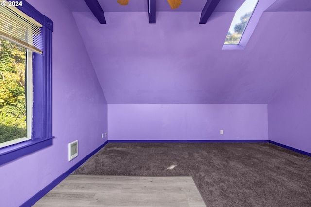 bonus room featuring light carpet, vaulted ceiling with skylight, and a wealth of natural light