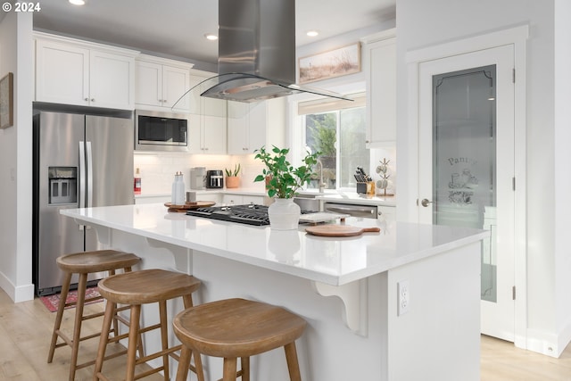 kitchen with island range hood, a center island, white cabinets, and stainless steel appliances