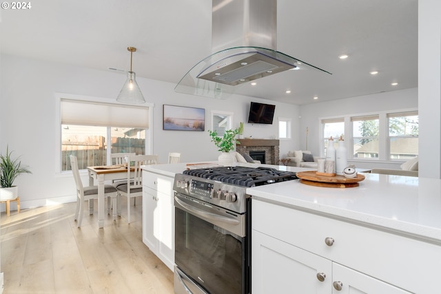 kitchen with stainless steel gas stove, white cabinets, a healthy amount of sunlight, and light wood-type flooring