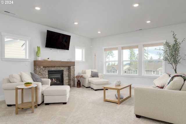 carpeted living room with a stone fireplace