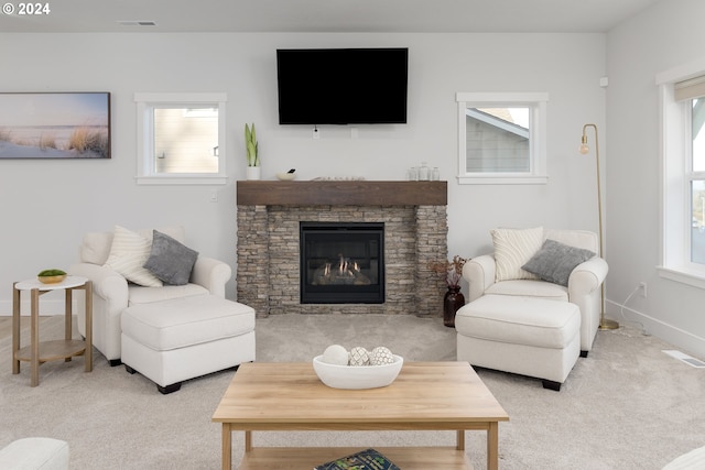 living room featuring a stone fireplace, a wealth of natural light, and light colored carpet