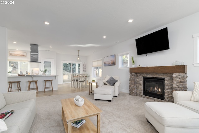 carpeted living room featuring plenty of natural light and a stone fireplace