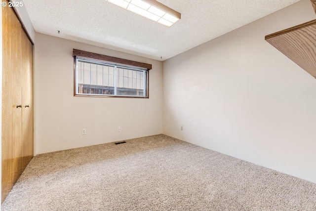 unfurnished room featuring a textured ceiling and carpet