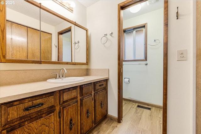 bathroom featuring wood-type flooring, vanity, and a textured ceiling