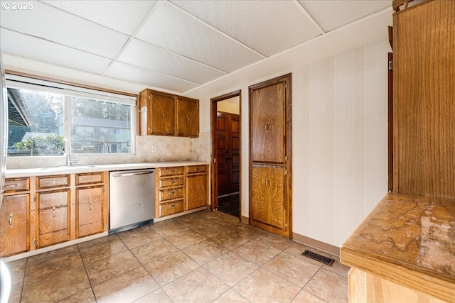 kitchen with stainless steel dishwasher, a paneled ceiling, tasteful backsplash, and sink