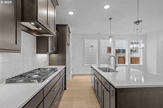 kitchen with sink, tasteful backsplash, an island with sink, pendant lighting, and stainless steel appliances