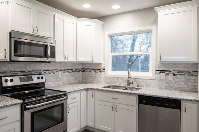 kitchen featuring light stone countertops, appliances with stainless steel finishes, white cabinetry, and sink