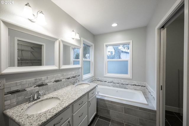 bathroom featuring vanity, tile patterned flooring, and a relaxing tiled tub