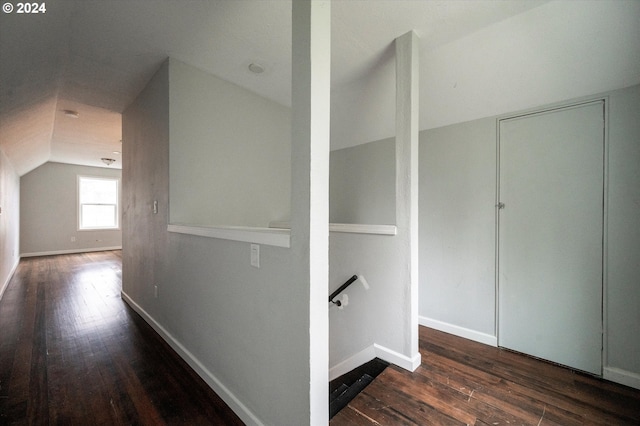 hallway with dark wood-type flooring and vaulted ceiling