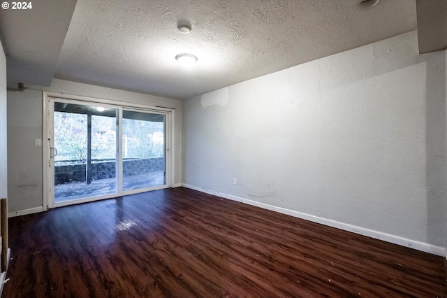 spare room featuring dark hardwood / wood-style floors and a textured ceiling