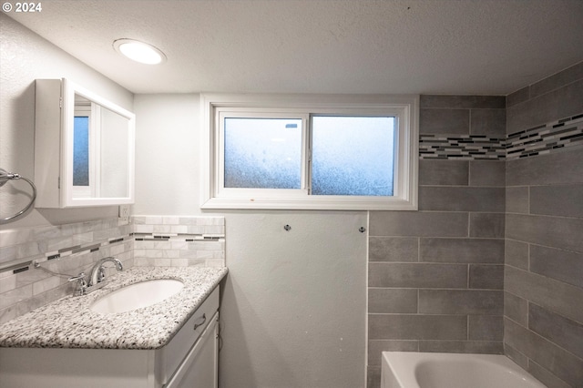 bathroom featuring a textured ceiling, decorative backsplash, vanity, and tiled shower / bath combo