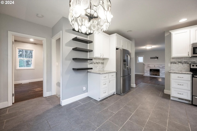 kitchen with white cabinets, decorative backsplash, stainless steel appliances, and a wealth of natural light