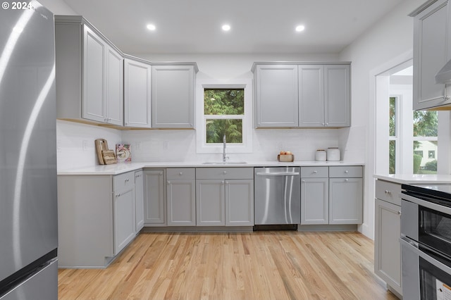 kitchen featuring gray cabinetry, sink, stainless steel appliances, and light hardwood / wood-style floors