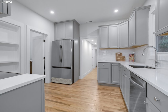 kitchen featuring gray cabinets, sink, stainless steel appliances, and tasteful backsplash