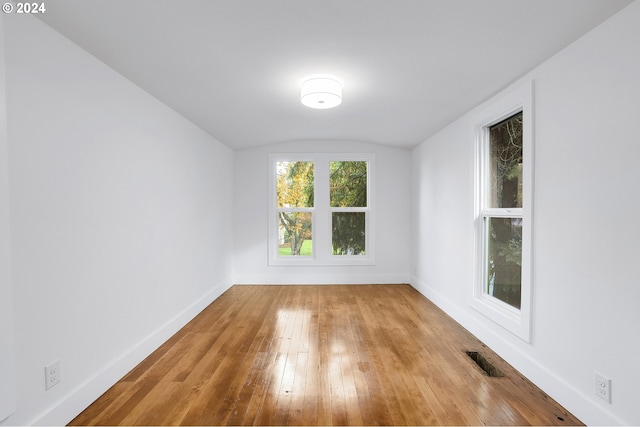 spare room with vaulted ceiling and light hardwood / wood-style flooring