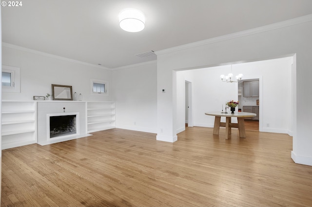 unfurnished living room featuring light hardwood / wood-style flooring, an inviting chandelier, built in features, and ornamental molding