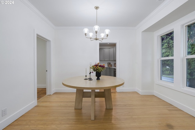 dining room with light wood-type flooring, crown molding, and an inviting chandelier